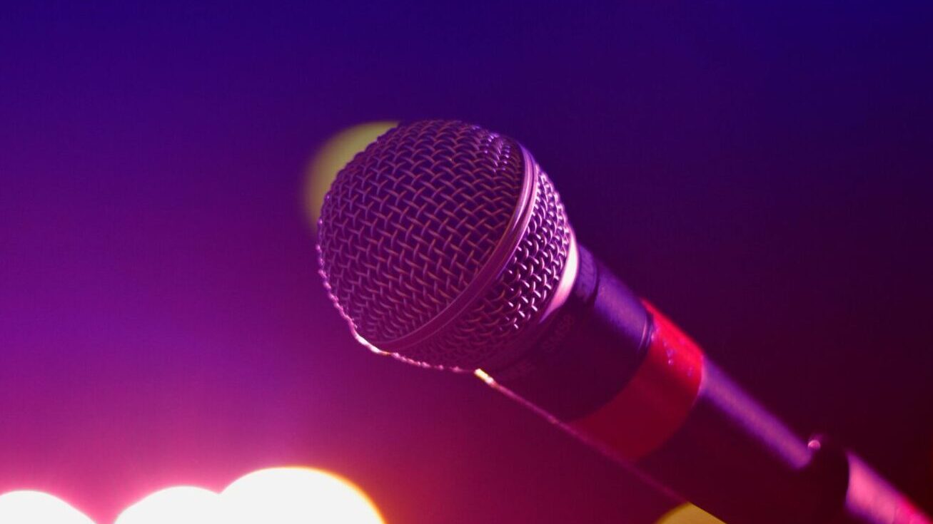 pexels-photo-144429-144429 Colorful stage lighting highlights a microphone in a close-up view, perfect for music and performance themes.
