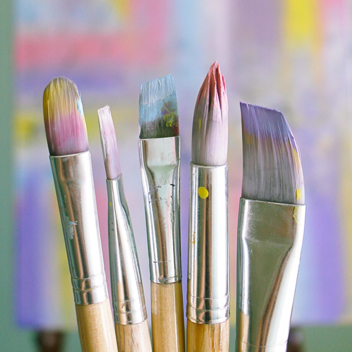 Art brushes with abstract painted canvas in vibrant colors.